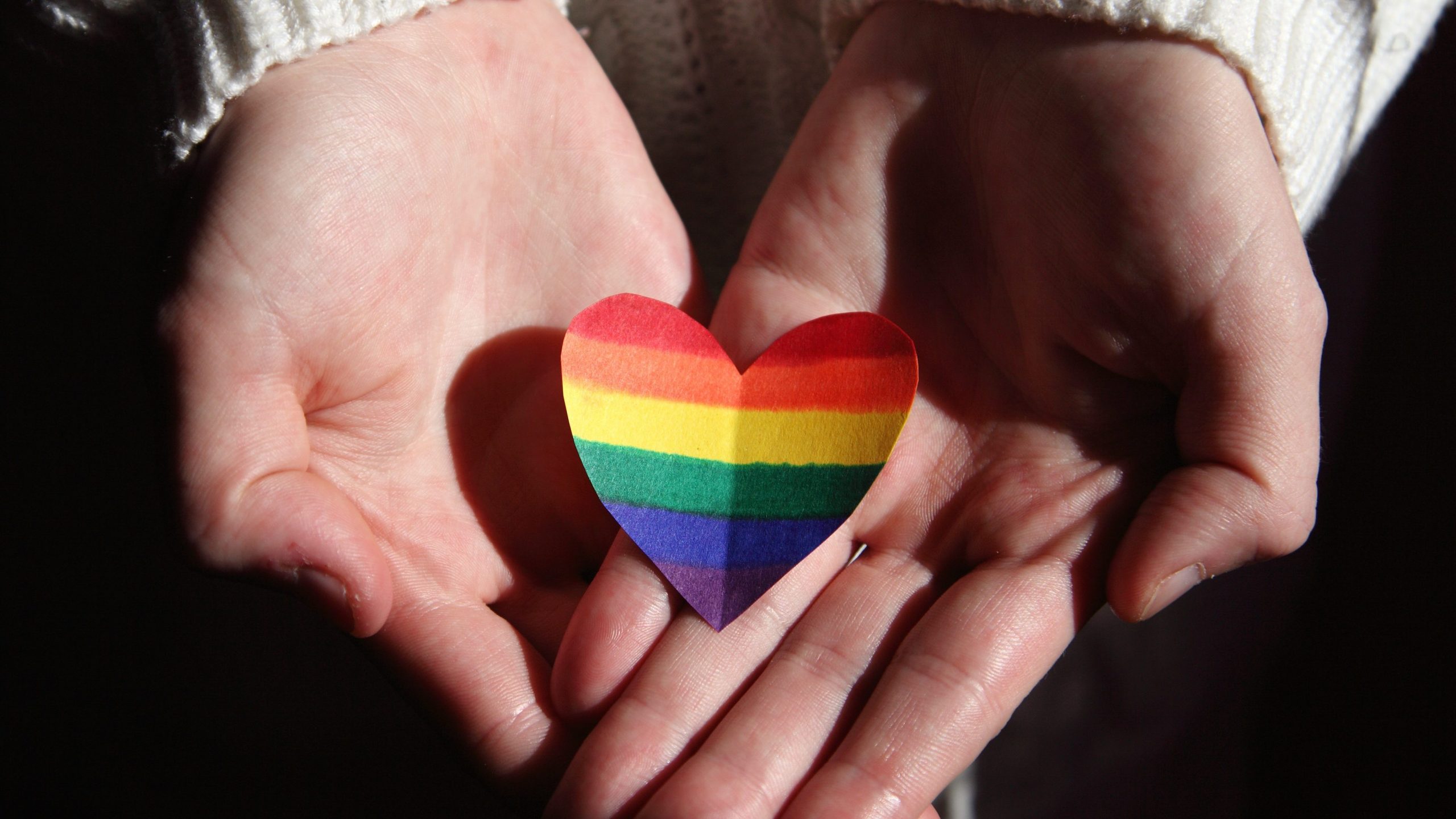 Hands holding a rainbow heart representing diversity in gender expression
